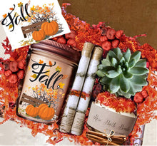 Load image into Gallery viewer, 
A fall-themed gift set includes a candle in a jar labeled "Fall" with pumpkin and leaf designs, two rolled bath salts, a succulent plant, a bath bomb, cinnamon sticks, and a note, all nestled in red and orange decorative filler.