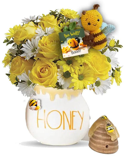 A cheerful arrangement of yellow roses, daisies, and white flowers in a honey pot vase labeled 