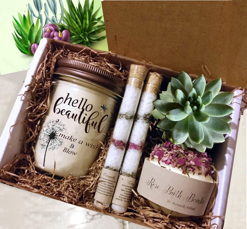 Gifts for Her and Unusual Gift Ideas for Women -A gift box containing a jar candle with "happy birthday" written on it, two tubes of bath salts, a bath bomb labeled "Rose" with dried petals, and a small green succulent plant, all nestled in brown shredded paper. Naturally GiftedNY