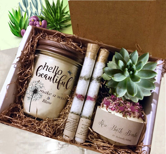 Gifts for Her and Unusual Gift Ideas for Women -A gift box containing a jar candle with "happy birthday" written on it, two tubes of bath salts, a bath bomb labeled "Rose" with dried petals, and a small green succulent plant, all nestled in brown shredded paper. Naturally GiftedNY